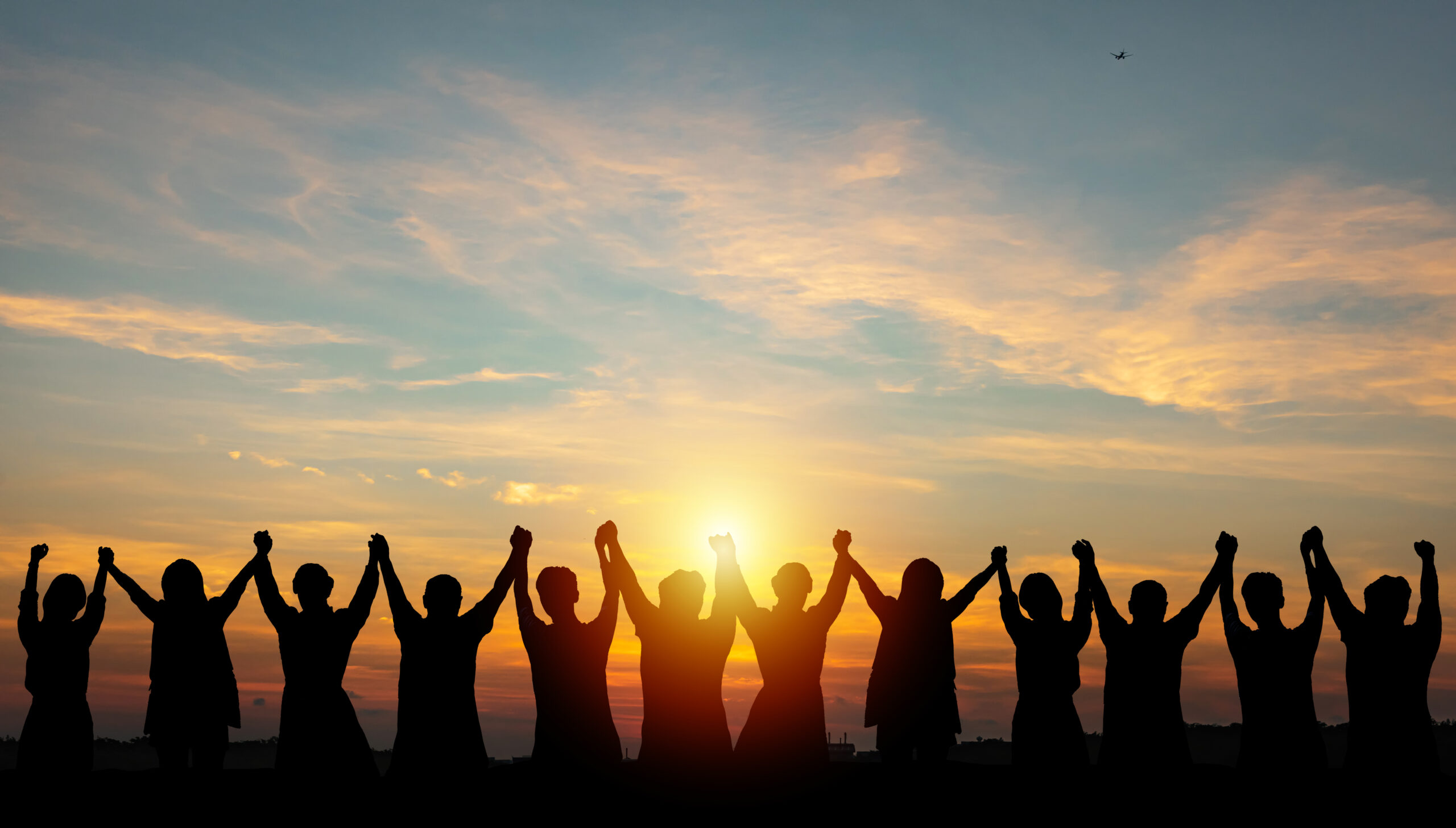 Silhouette of group business team making high hands over head in sunset sky evening time for business success and teamwork concept in company growth mergers and acquisitions start greeting etiquette